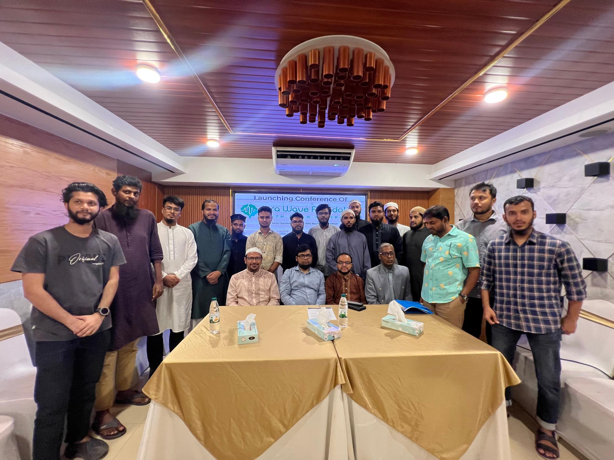 Members, guests and volunteers of Iqra Wave Foundation gathered in front of the Launching Conference banner in Dhaka.
